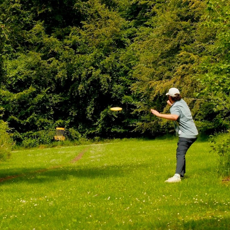 Man in a grassy woodland area playing disc golf