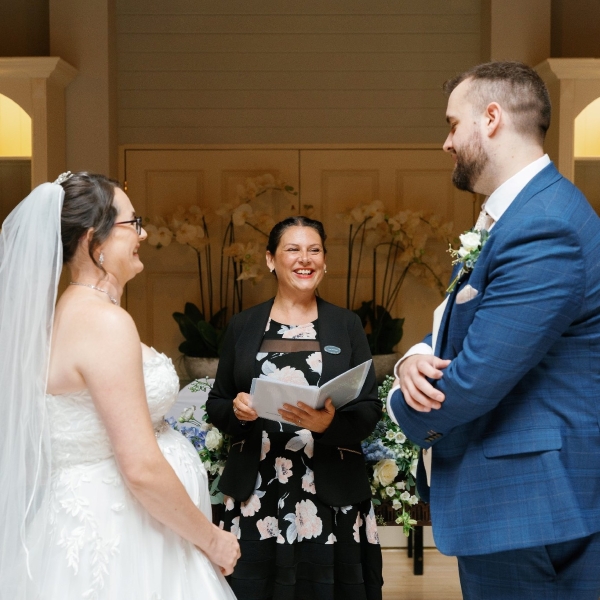 A happy wedding couple standing in front of a celebrant