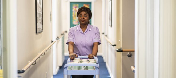 A healthcare worker wheeling a trolley