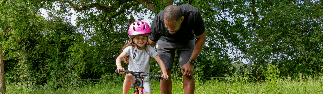 A man helping a young girl ride a bike