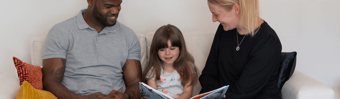 Two adults reading with a child